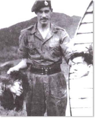 Chi è jihadista? Un soldato Britannico mostra con orgoglio le teste di due contadini malesi che aveva personalmente decapitato. circa 1950